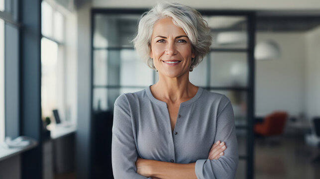 A smiling confident mature middle aged woman standing in a modern office.