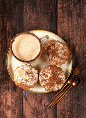 Chocolate muffins with nutmeg and cinnamon eggnog on a wooden background, cozy breakfast concept, advertising for a cafe or bakery. Warming egg drink in cold season with delicious dessert,