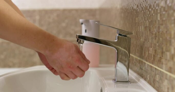 Man washes his hands with foamy soap in the bathroom. Daily hygiene routine