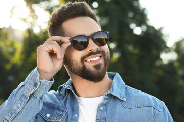Handsome smiling man in sunglasses outdoors on sunny day