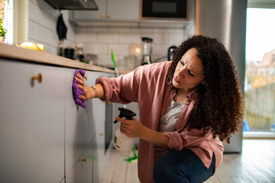 Woman cleaning kitchen with spray bottle and cloth