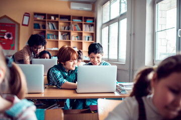 Children having computer class using laptop in classroom