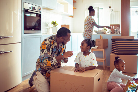Father packing valuables in box during moving day with daughter