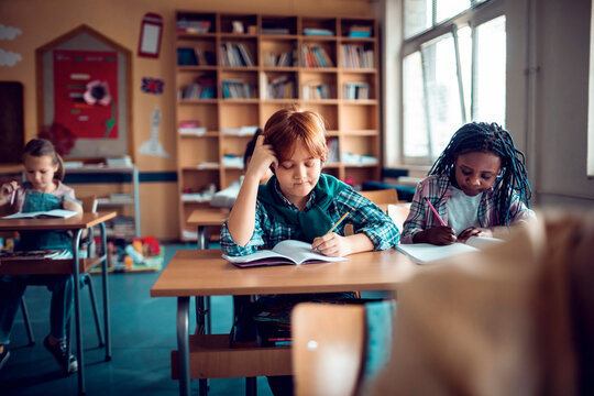 Diverse children writing notes in elementary classroom