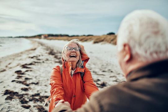 Happy senior couple holding hands on the beach