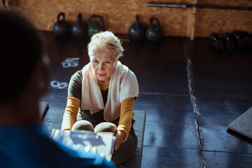 Senior woman working out with personal trainer in gym