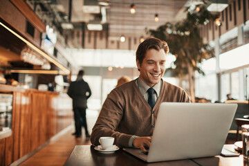 Young businessman working on laptop and sitting in cafe