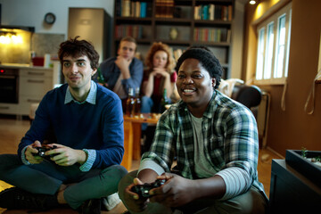 Young friends playing console video games at home