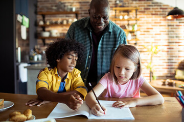 Father helping his diverse multiethnic kids with homework at home
