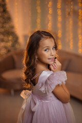 Fototapeta premium beautiful Girl in an elegant fluffy princess dress in a home interior against the background of a Christmas Tree