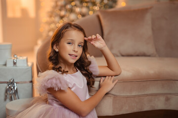 beautiful Girl in an elegant fluffy princess dress in a home interior against the background of a Christmas Tree © Daria