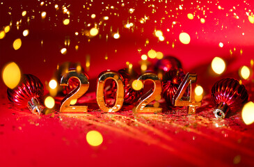 2024 gold colored numbers and glittering confetti on a vivid bright red background. New Year...