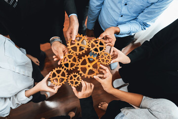 Group of multiracial business people joining gear wheels together as effective unity and productive teamwork concept. Efficient system business team process for solution solving. Meticulous - obrazy, fototapety, plakaty