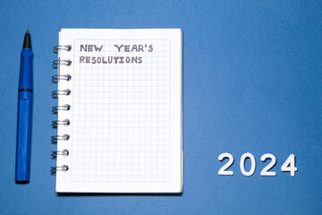 Blank New Year's resolution list in a small notebook on a flat blue background. Goals for the year...