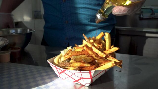 Chef adding truffle oil to a basket of fresh french fries