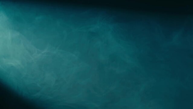 Abstract background of chaotically blending puffs of blue smoke on a black background. Realistic fog in blue neon light close up. Texture and abstract art. Copy space.