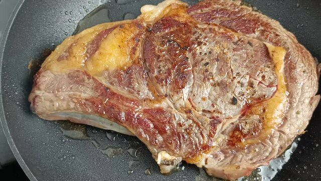 cuisson de c&ocirc;te de boeuf dans une po&ecirc;le, en gros plan