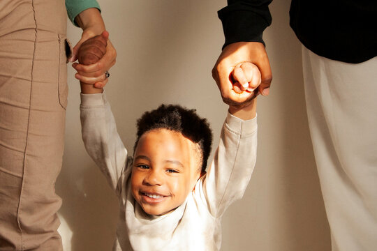 Portrait of little black boy holding his parents' hands