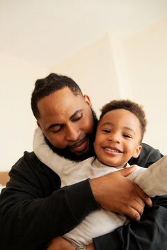 Portrait of black father and son smiling into camera