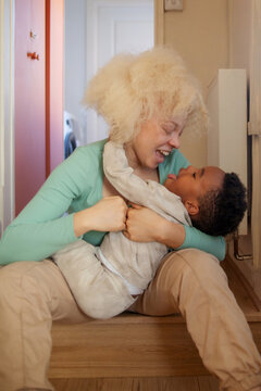 Happy mother and son playing and laughing in hallway