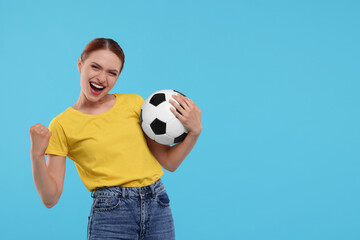 Emotional fan holding football ball and celebrating on light blue background, space for text