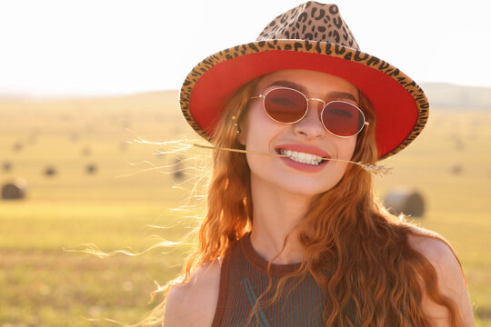 Beautiful happy hippie woman with spikelet in field, space for text