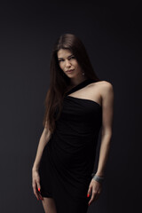 Naklejka premium Portrait of a woman adorned in a black one-shoulder dress with confident stare