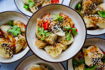 Plates of fish salad with vegetables, herbs, tomatoes and sesame seeds. 
