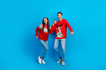 Full body photo of attractive young couple have fun clobbers dancer wear x-mas ornament red sweaters isolated on blue color background