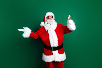 Photo of positive funky claus wear red costume telling christmas wishes drinking champagne isolated green color background