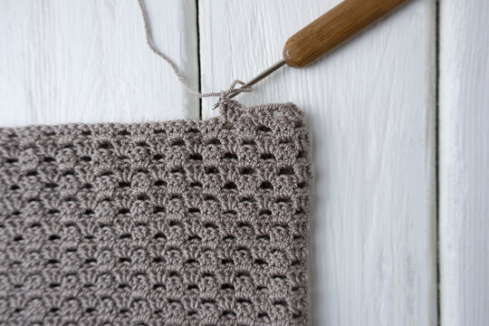 Knitting process, crocheting. The concept of creating a product with your own hands. Crochet pattern pattern, scissors and hook on a light wooden background,