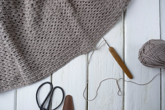 Knitting process, crocheting. The concept of creating a product with your own hands. Crochet pattern pattern, scissors and hook on a light wooden background, - Powered by Adobe