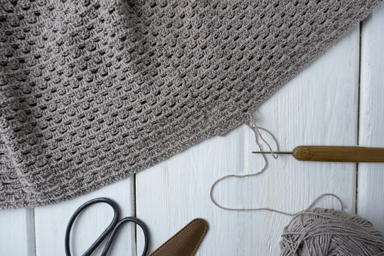 Knitting process, crocheting. The concept of creating a product with your own hands. Crochet pattern pattern, scissors and hook on a light wooden background,