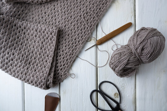 Knitting process, crocheting. The concept of creating a product with your own hands. Crochet pattern pattern, scissors and hook on a light wooden background,