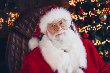 Photo of charming handsome santa claus wear red costume sitting leather chair smiling indoors north pole office