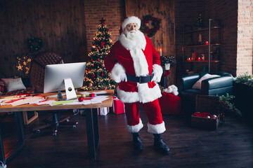 Photo of confident handsome santa claus wear red costume enjoying working indoors new year north pole office