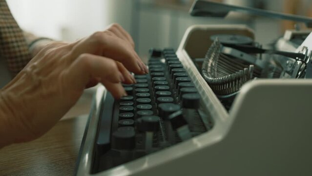 Well-groomed hands of middle-aged woman with nude manicure using vintage writing tool for typing text. Skillful female typewriter during work at home. High quality 4k footage