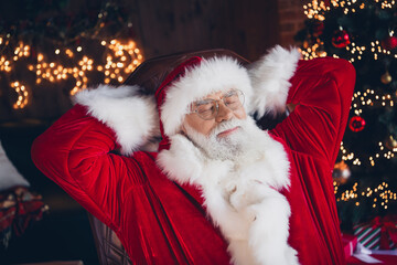 Photo of handsome dreamy santa claus wear red costume sitting leather chair closed eyes arms behind...