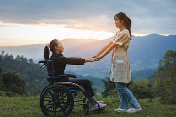 Happy young mother in wheelchair with daughter in spring nature at sunset.