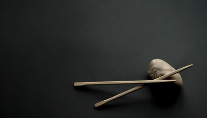 Japanese bamboo chopsticks and light stone on dark gray background. Minimalism, one corner composition, wide copy space. No people