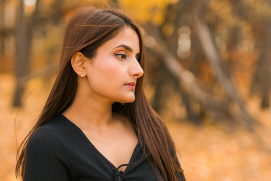 Beautiful indian woman generation z relaxing and feeling nature at autumn park in fall season. Diversity and gen z youth