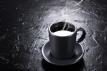 Cup of hot coffee on a black table.