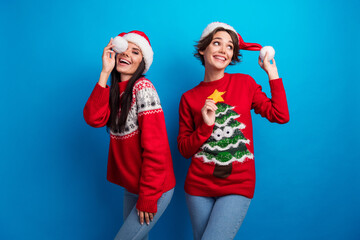 Photo of cheerful girls dancing celebrate winter x mas christmas discounts isolated blue color...