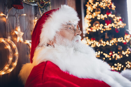 Photo of cheerful thoughtful santa claus wear red costume spectacles enjoying decorations indoors new year north pole office - Powered by Adobe