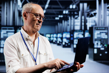 Senior IT developer inspects supercomputers in data center, ensuring smooth performance. Capable...