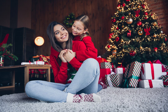 Photo of positive dreamy little siblings dressed red sweaters having fun together embracing indoors christmas apartment home