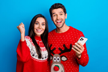 Photo portrait of lovely young spouses celebrate lottery device wear x-mas ornament red sweaters isolated on blue color background - obrazy, fototapety, plakaty