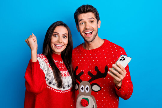 Photo portrait of lovely young spouses celebrate lottery device wear x-mas ornament red sweaters isolated on blue color background