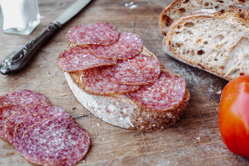 Sliced salami on rye bread with tomato.