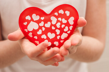 Fototapeta premium girl's hands holding red and white heart. Horizontal. faceless. Valentines day.
